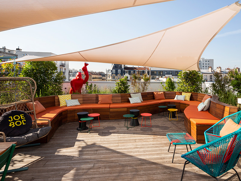 Outside rooftop terrace with brightly coloured seating and blue sky