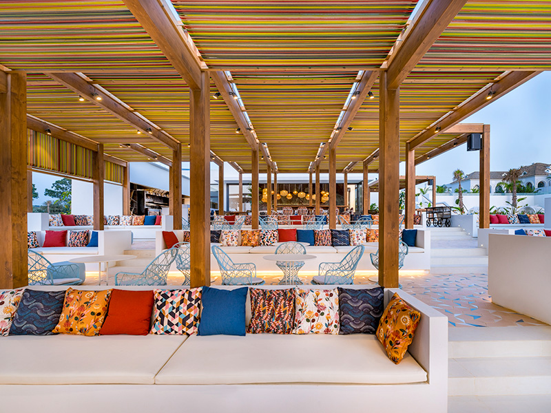 White sofas with multi-coloured cushions under a canopy on an outside terrace