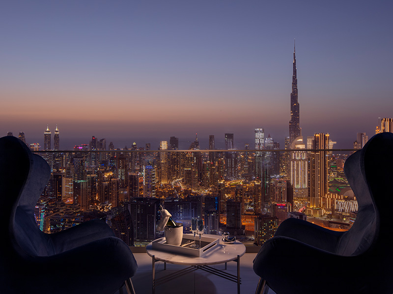 Two grand lounge seats overlooking the dramatic skyline of Dubai at dusk
