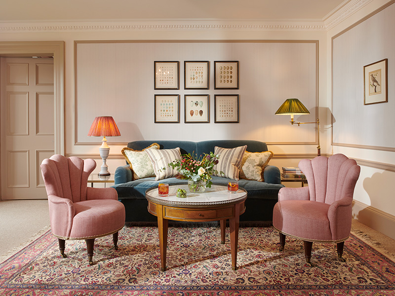 A comfortable seating area in a bright room with pastel colours and a large patterned rug on the floor