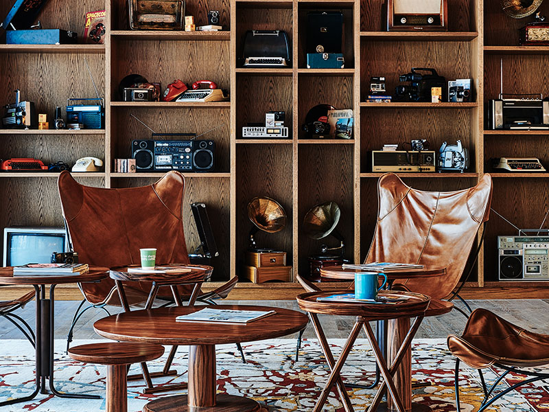 A wall of wooden shelving sits behind two chairs around a coffee table