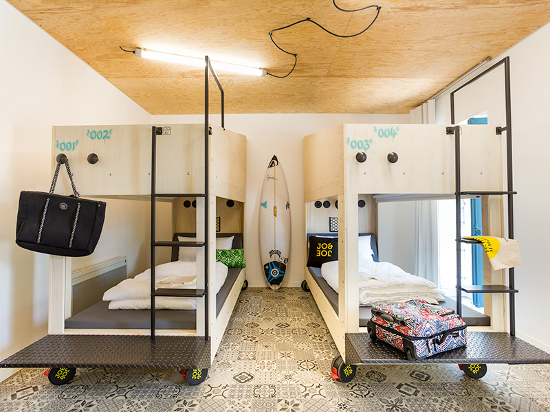 Two sets of bunk beds on wheels, with a surf board in the background.