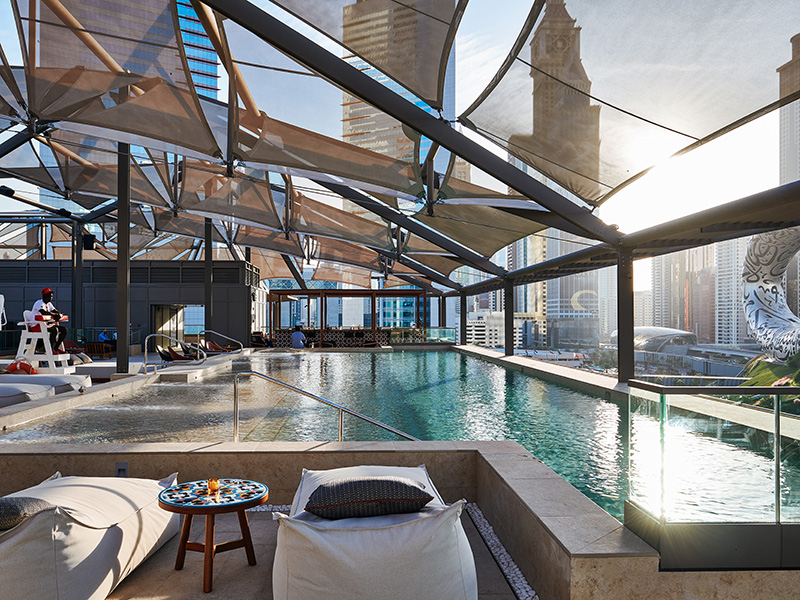 Swimming pool on a rooftop with lounge chairs around the edge