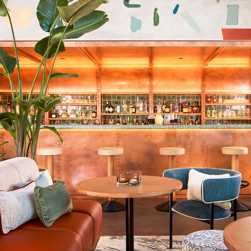 Seating in front of a bar with a brass roof and sage green tiles