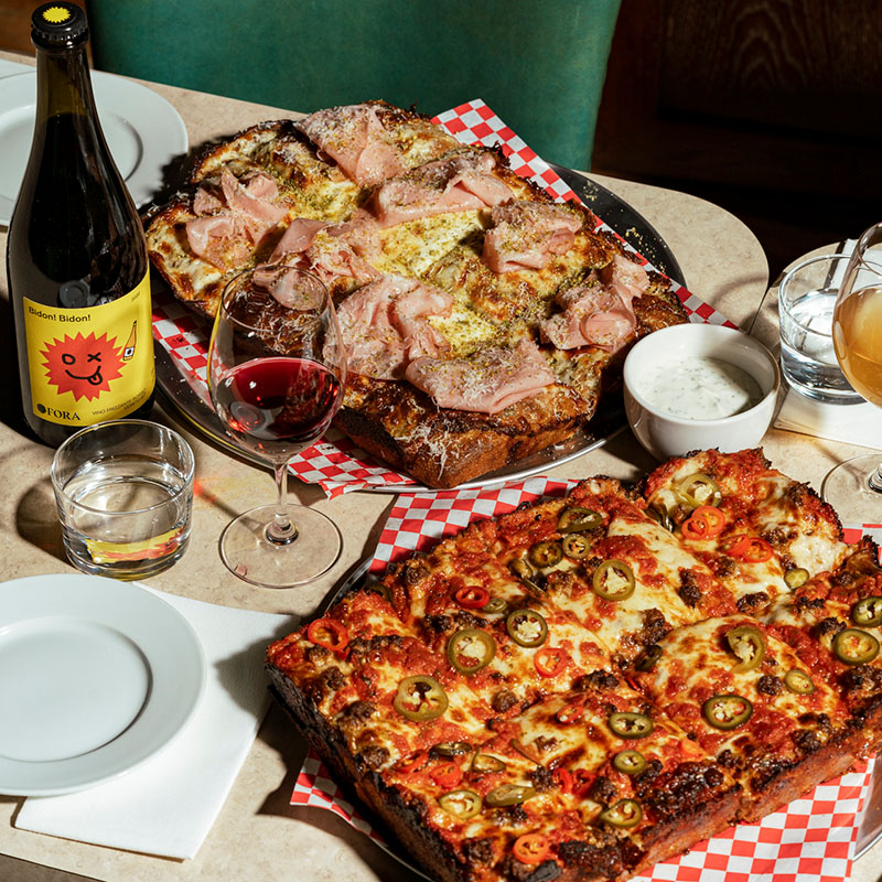 Two large deep dish pizzas served with wine and dipping sauce